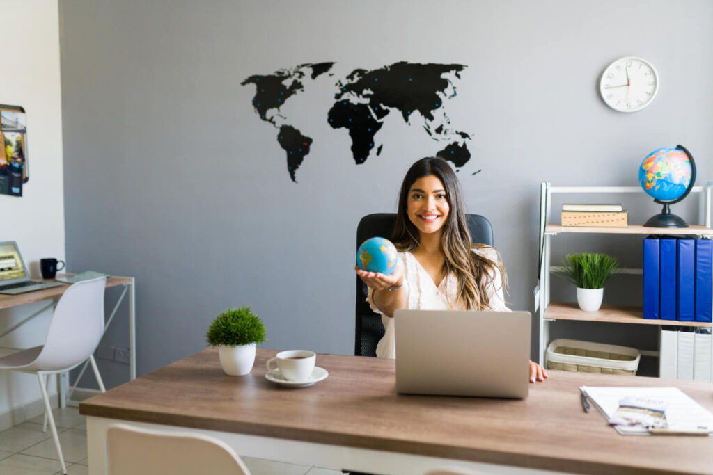 holding-world-my-hands-attractive-female-travel-agent-showing-globe-smiling-while-working-her-modern-office