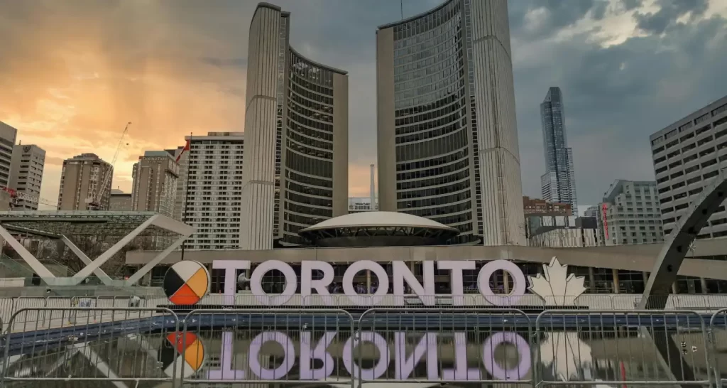 Toronto Signage Near Buildings Under White Clouds