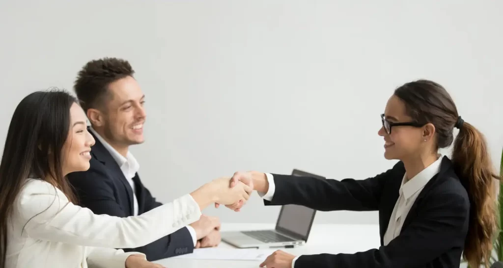 Smiling diverse businesswomen shake hands at group meeting, deal concept