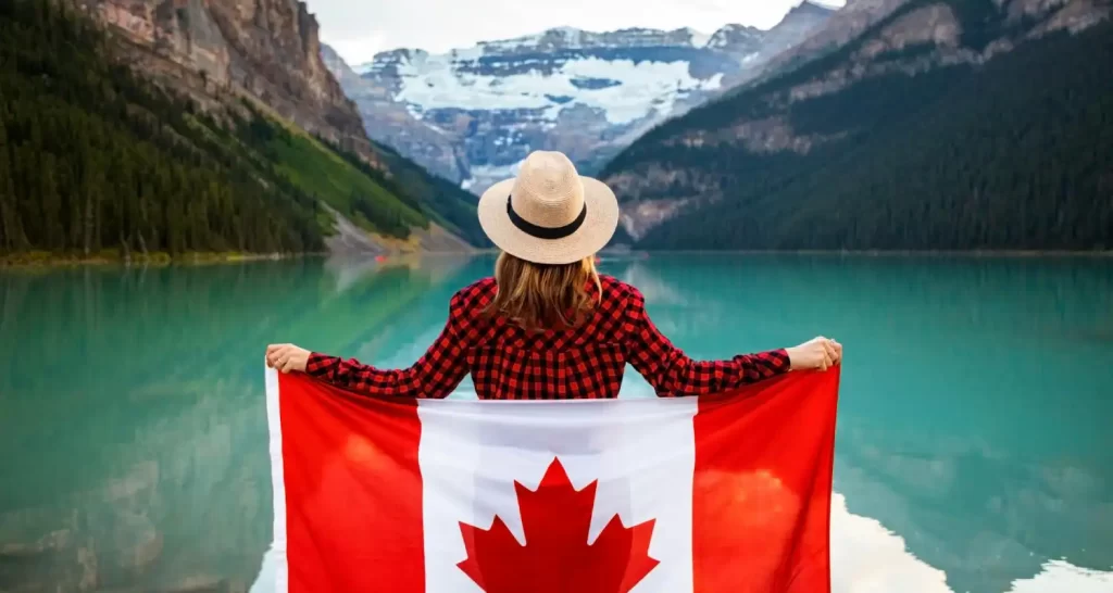 woman-wearing-red-and-black-checkered-dress-shirt-and-beige-fedora-hat-holding-canada-flag