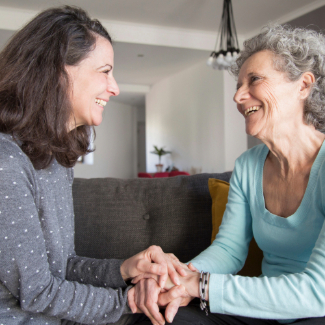 Elderly woman and her daughter laughing and holding hands