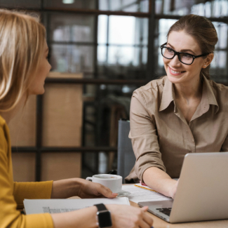 Smiley businesswomen working with laptop at desk
