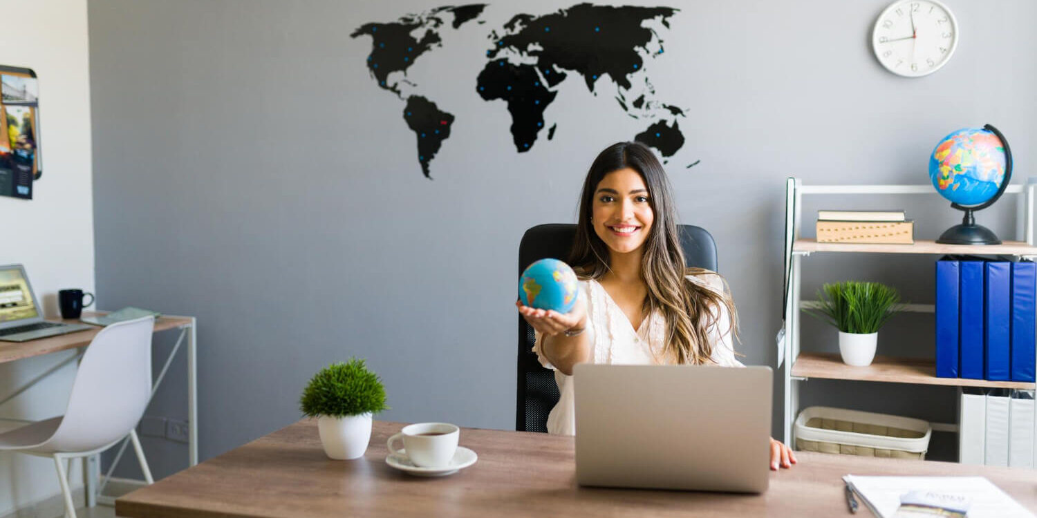 holding-world-my-hands-attractive-female-travel-agent-showing-globe-smiling-while-working-her-modern-office