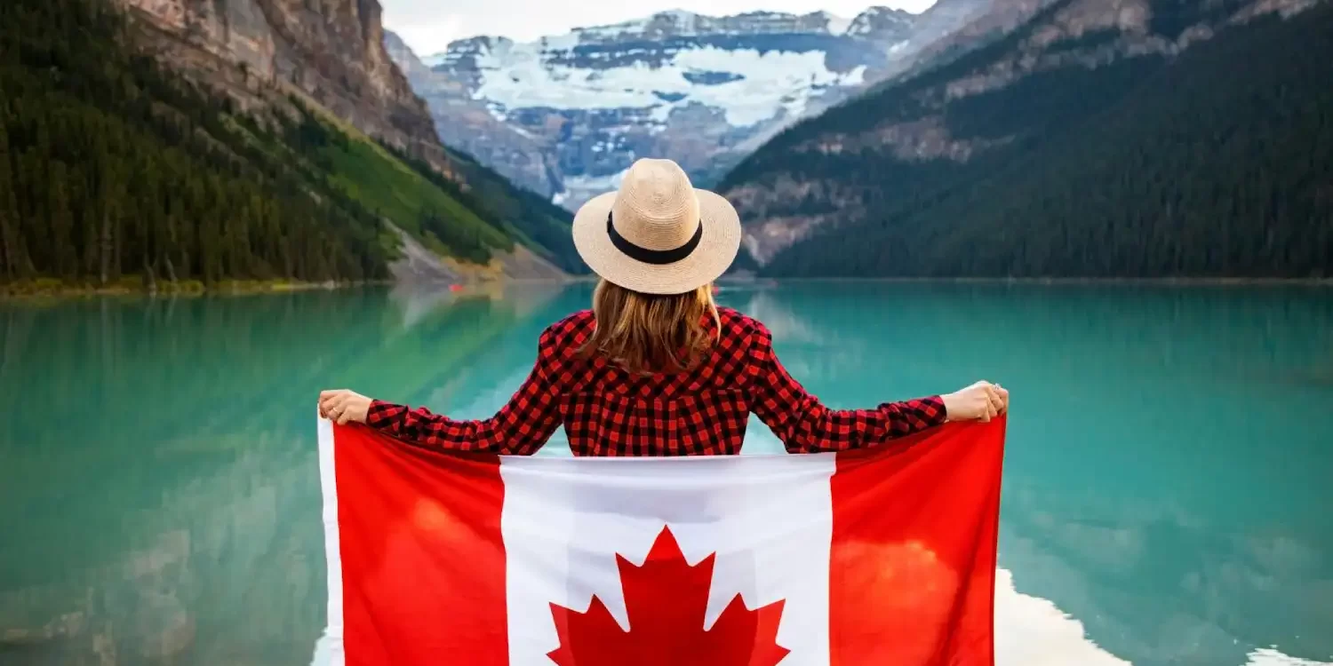 woman-wearing-red-and-black-checkered-dress-shirt-and-beige-fedora-hat-holding-canada-flag